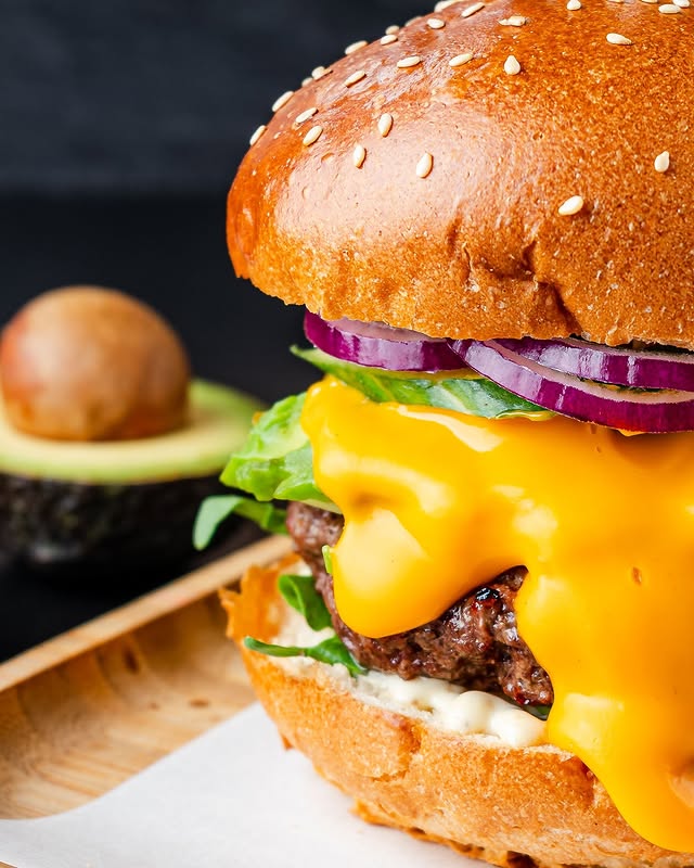 Saftiger Cheeseburger mit geschmolzenem Cheddar, frischem Salat und roten Zwiebeln im Burger House Köln