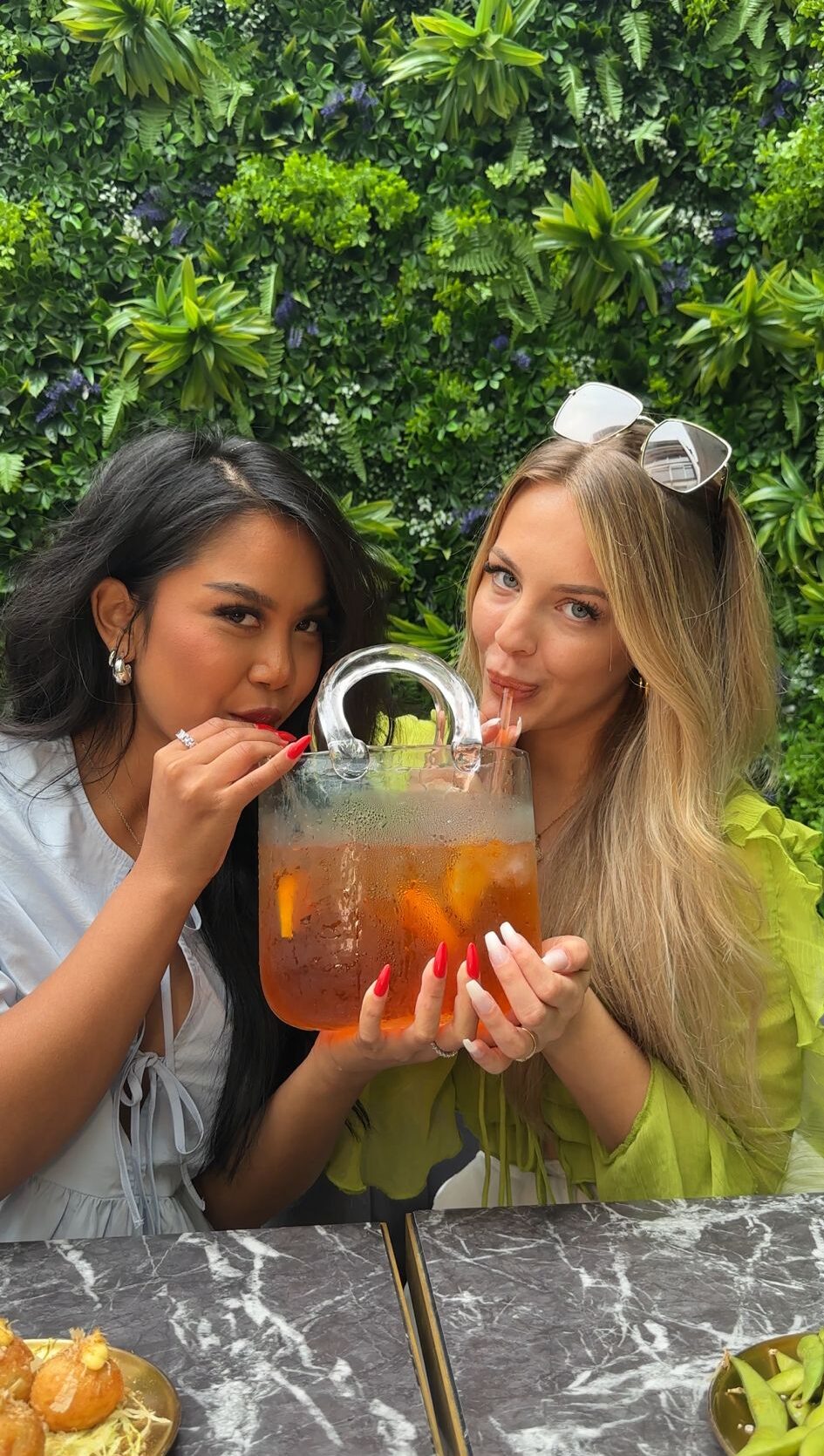 Zwei Frauen trinken gemeinsam Aperol Spritz aus einem Krug im Oishinbo Dortmund