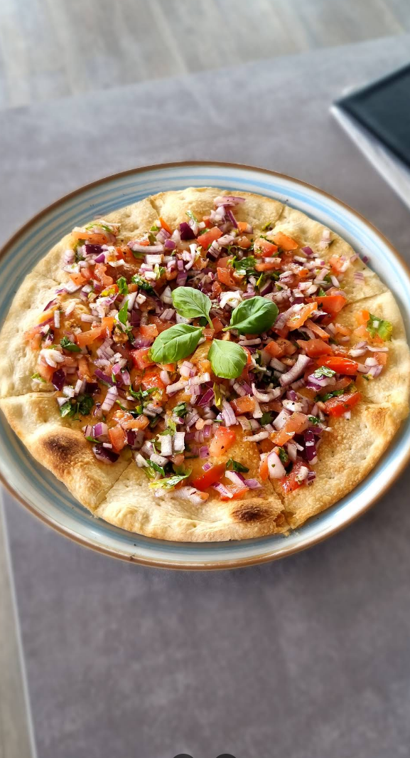 Frische Pizza mit Tomaten, roten Zwiebeln, Kräutern und Basilikum bei Buonissimo Krefeld