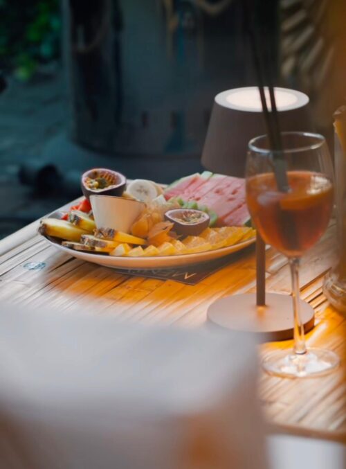 Obstplatte mit exotischen Früchten und Cocktail bei stimmungsvoller Beleuchtung im Außenbereich von Vakis Duisburg